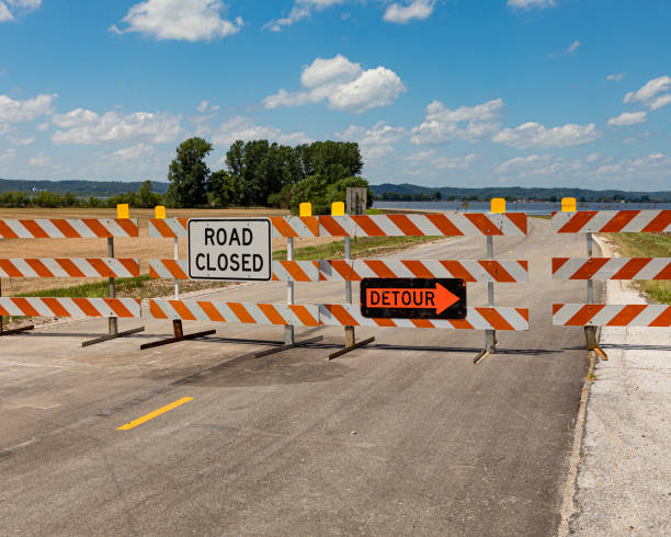 Barricades and signs warn of a road closed due to flooding along the Mississippi River looking across the Mississippi River flooding from Illinois toward Missouri barricade photos stock pictures, royalty-free photos & images
