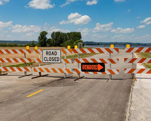 Photo of Barricades and signs warn of a road closed due to flooding along the Mississippi River