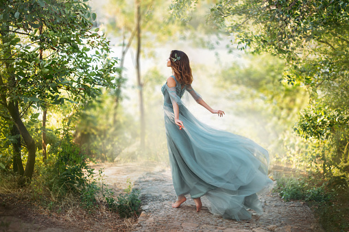 istock delightful light girl in sky blue turquoise dress with long flying train, princess of wind and daughter of storm, lady with dark hair throws fallen leaves to ground, autumn story in art processing 1163568324
