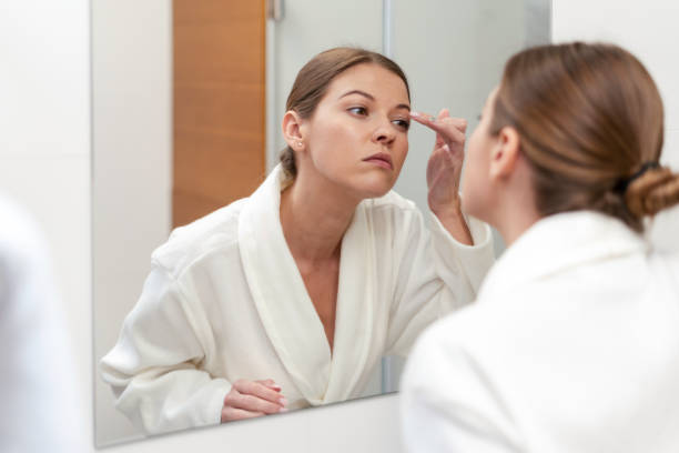 istock Woman in bathrobe looking in mirror at bathroom 1163569800