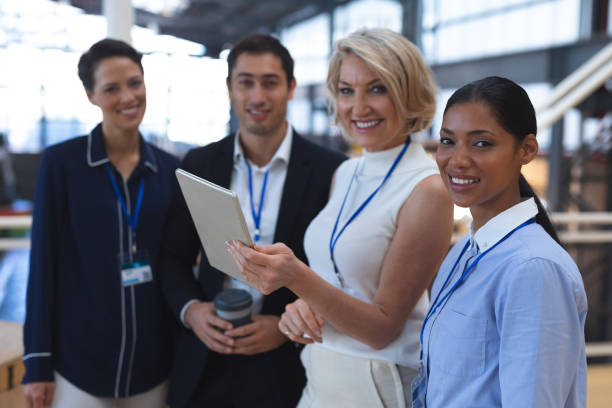 istock Business people looking at camera while discussing over digital tablet in a modern office 1163569807