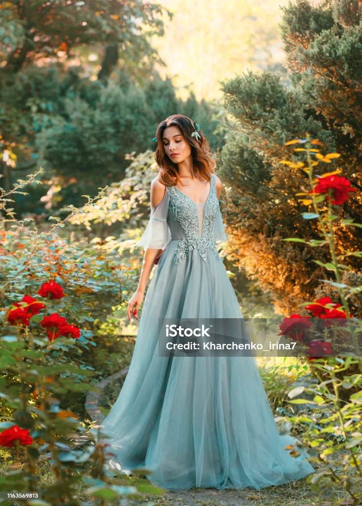 Slender Lady In Light Turquoise Summer Dress With Cut On Chest And Open Shoulders Princess With Dark Hair Looks Out Prince In Park Girl With Bright Smile Positive Emotions Art Portrait Of Slender Lady In Light Turquoise Summer Dress With Cut On Chest And Open Shoulders Princess With Dark Hair Looks Out Prince In Park Girl With Bright Smile Positive Emotions Art Portrait Of
