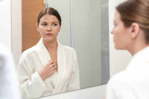 istock Woman in bathrobe looking in mirror at bathroom 1163569847