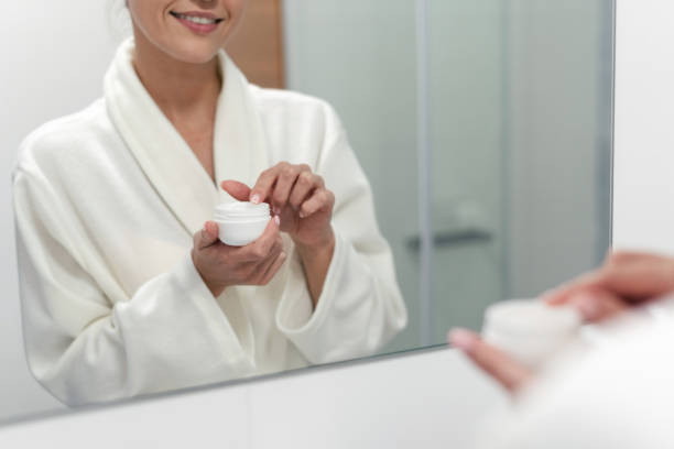 istock Woman holding cream in hands, standing at bathroom 1163569915
