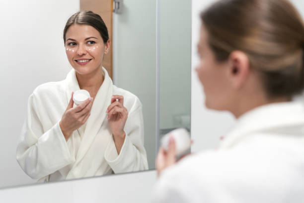 istock Woman holding cream in hands, standing at bathroom 1163569999