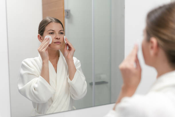 istock Woman in white bathrobe holding cotton pad in hands 1163570021