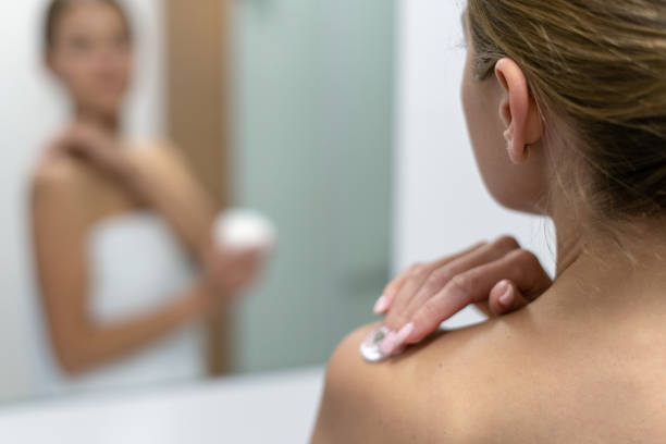 istock Woman applying body cream on shoulder in bathroom 1163570053