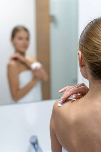 istock Woman applying body cream on shoulder in bathroom 1163570088