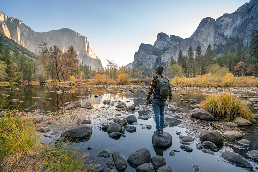 Young man contemplating Yosemite valley from the river, reflections on water surface