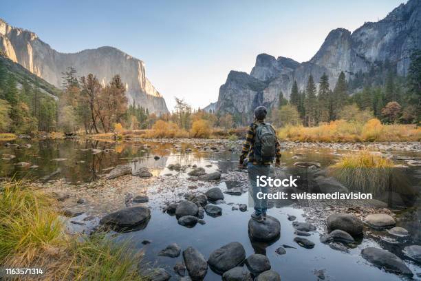 Young Man Contemplating Yosemite Valley From The River Reflections On Water Surface Stock Photo - Download Image Now