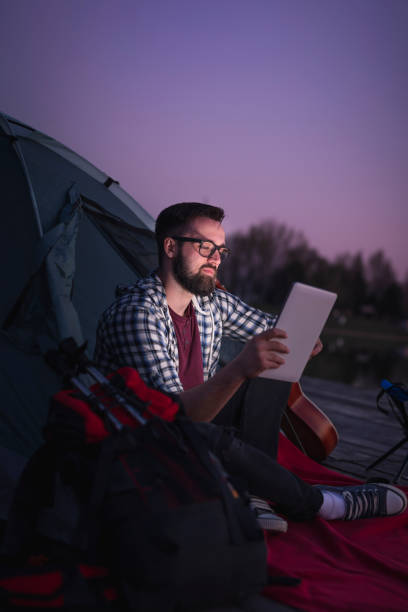 freelancer camping by the lake - hipster people surfing the net internet imagens e fotografias de stock