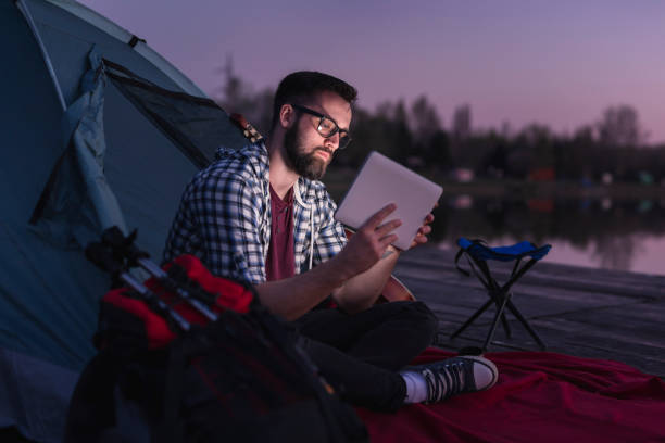 freelancer camping on the lake docks - hipster people surfing the net internet imagens e fotografias de stock