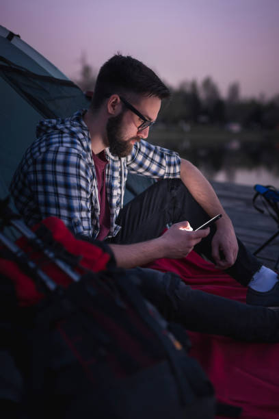 man camping on the lake docks - hipster people surfing the net internet imagens e fotografias de stock