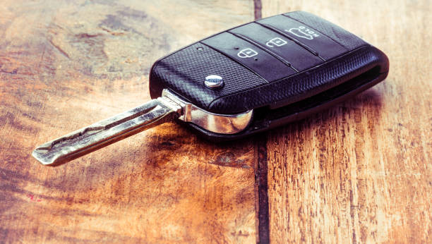 istock Black car key isolated on wooden background 1163575306