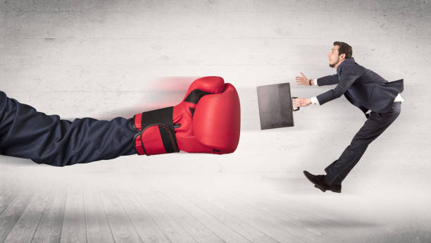 istock Arm with boxing gloves hits office worker concept 1163579384