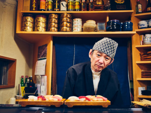 A Japanese sushi chef serving customers in a small sushi shop in Tokyo, Japan.