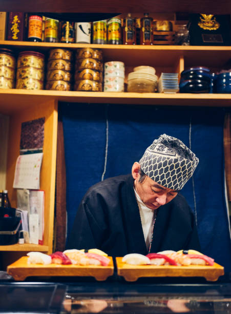 A Japanese sushi chef serving customers in a small sushi shop in Tokyo, Japan.