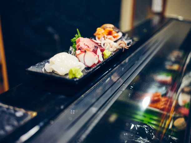 A Japanese sushi chef serving customers in a small sushi shop in Tokyo, Japan.