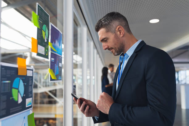 istock Businessman using mobile phone near glass wall in office 1163581349