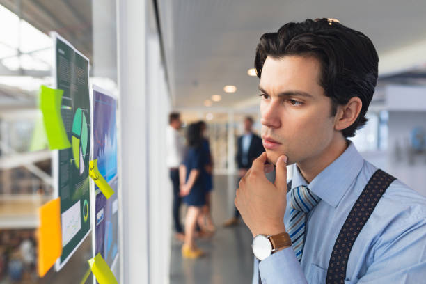 istock Businessman looking at sticky note and graph in office 1163581924