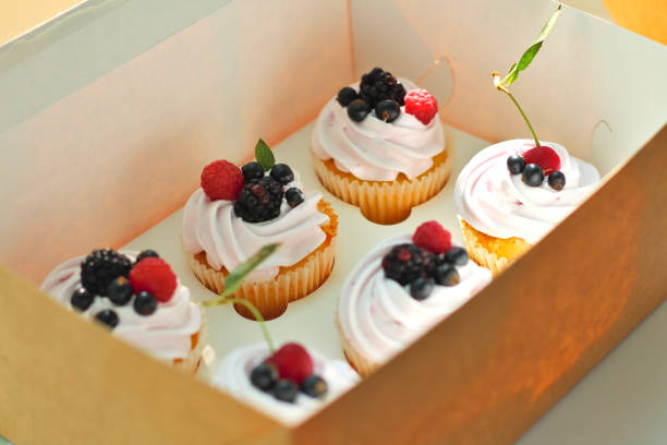 istock Isolated cupcakes with cream, cherry with a leaf, blackberry, raspberry black currant in a crafting box on a white background. 1163588437
