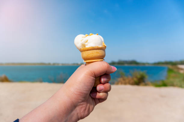 istock Hand with ice cream on blurred blue sky nature background 1163590628