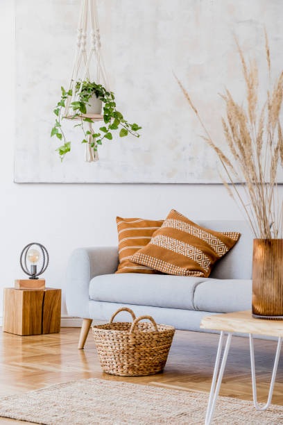 istock The modern boho compostion at living room interior with design gray sofa, wooden coffee table, rattan basket and elegant personal accessories. Honey yellow pillow and plaid. Cozy apartment. Home decor 1163592059