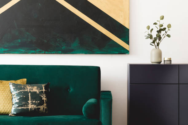 istock Stylish composition of home interior design with modern velvet sofa, navy blue shelf, pillows, flowers in vase, elegant accessories and geometric paintings on the wall. Nice home decor. Template. 1163592649