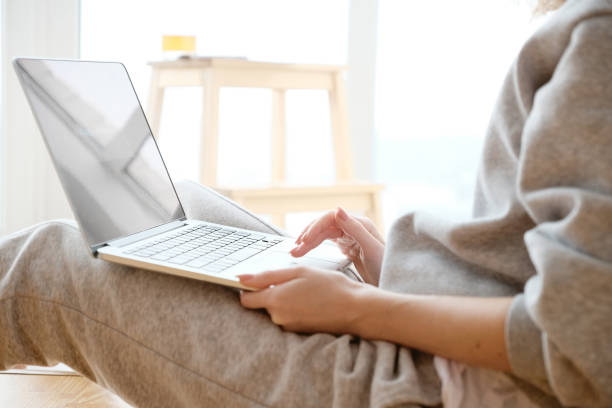 istock Smiling woman working on laptop in pyjamas 1163592741
