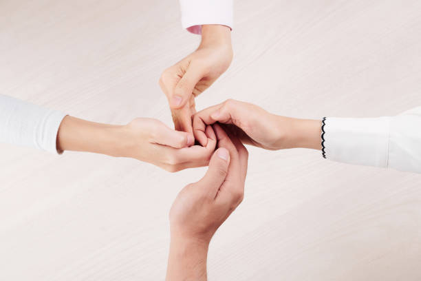 Close-up of family of four holding hands and demonstrating unity of their relationship isolated on white background