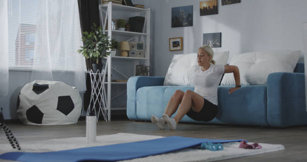 Young woman training at home Full shot of a young woman doing triceps dips at home woman pushing tire stock pictures, royalty-free photos & images