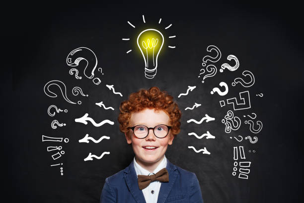 istock Laughing child boy with lightbulb and question marks on blackboard background 1163598168