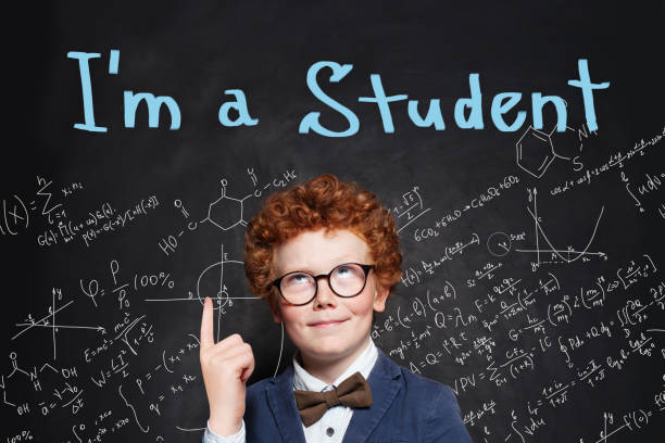 istock Smart student boy pointing finger on chalkboard background with I'm student text. Back to school concept 1163598184