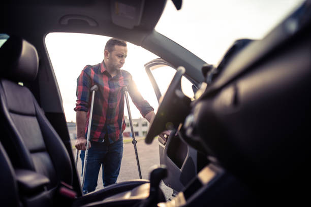 Man using crutches is about to take the car Man using crutches is about to take the car. view from inside the car standing had to knee pose stock pictures, royalty-free photos & images