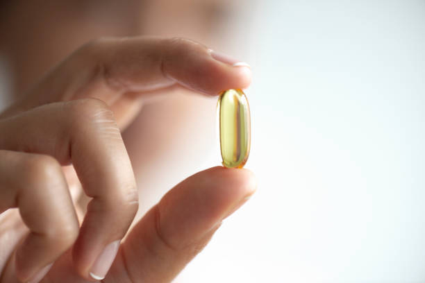 ソフトジェルカプセルを持つ女性 - fish oil pill healthy lifestyle protection ストックフォトと画像