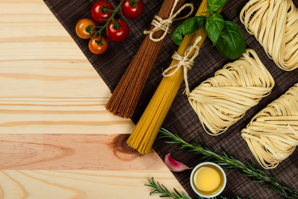 istock Composition with different types of pasta on pine wood background. Space for text. 1163604103