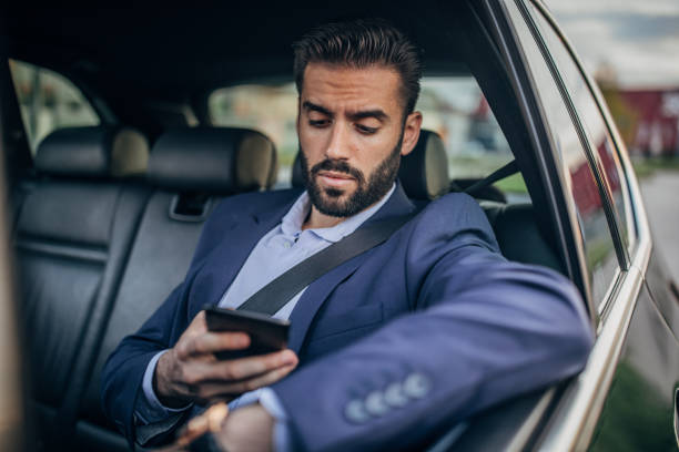 istock Handsome businessman driving in a car and text messaging 1163607319