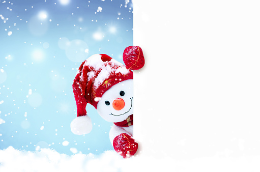 Little snowman in caps and scarfs on snow in the winter. Festive background with a funny snowman. Christmas card, copy space.