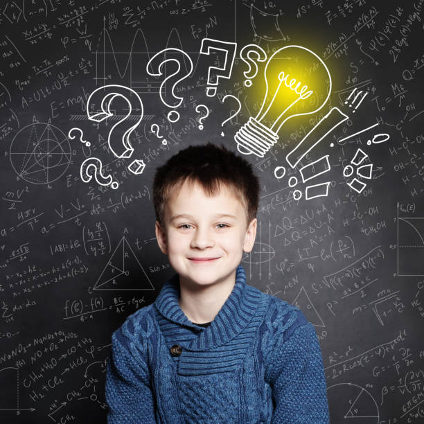 istock Smiling Child school boy with lightbulb on background with formulas 1163610613