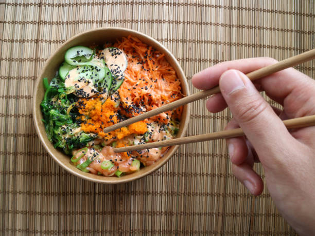 istock Hand with chopsticks taking salmon from a Hawaiin poke 1163613567