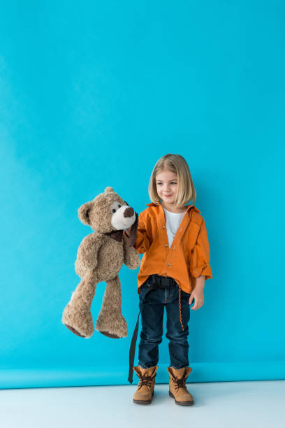 istock smiling and adorable kid holding teddy bear on blue background 1163619559