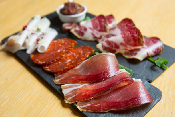 istock different kinds of cut ham on a wooden board 1163621575
