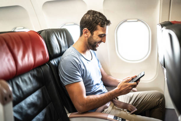 istock Side view of a man in an airplane using cellphone 1163622572