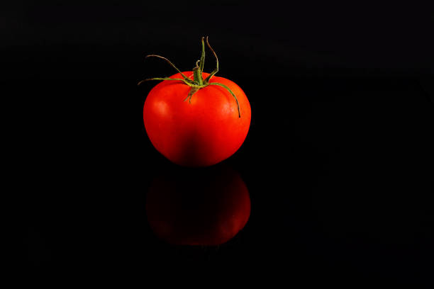 istock Red mini tomato on black reflective studio background. Isolated black shiny mirror mirrored background for every concept. 1163628789