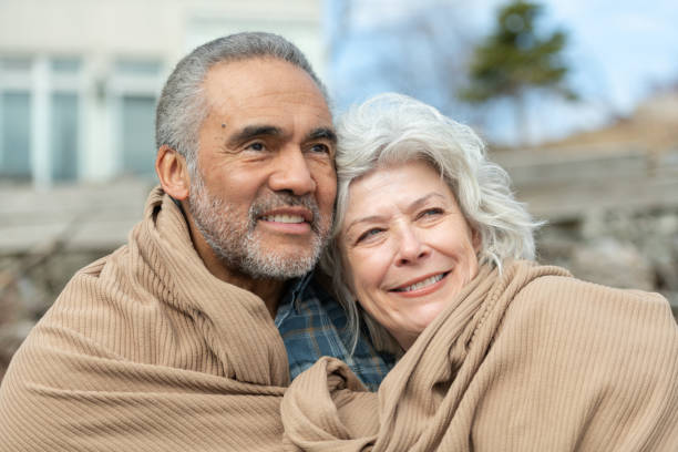 istock Senior couple wrapped in a blanket on a beach 1163630147