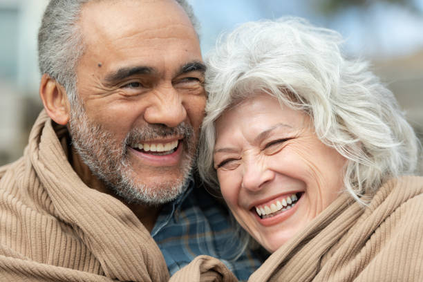 istock Senior couple wrapped in a blanket on a beach 1163630148