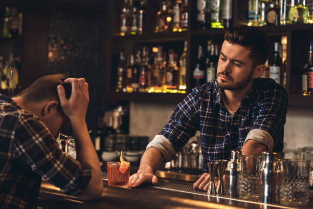 istock Young bartender standing at bar counter giving cocktail to sad client 1163630932