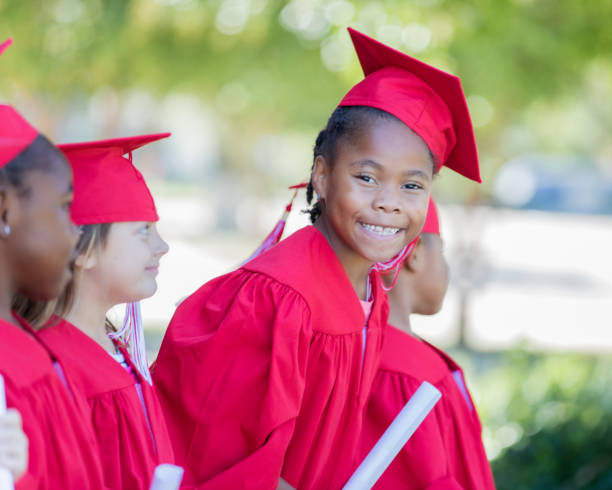 istock Adorable elementary age child wearing graduation cap and gown smiles during ceremony 1163631163
