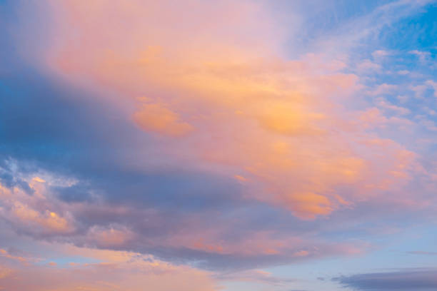 Blue sky with clouds glowing in orange hues at sunset