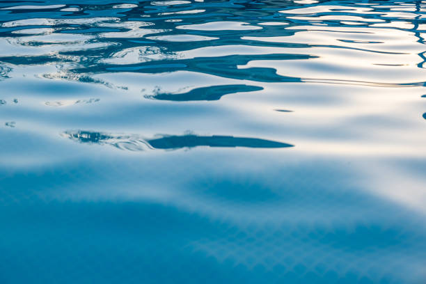 istock Ripples in pool blue water with light and shadow play background 1163634324